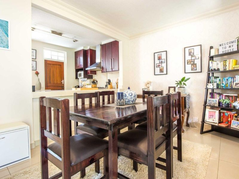 Open plan dining area adjacent to a kitchen featuring dark wood cabinetry and tiled flooring throughout.