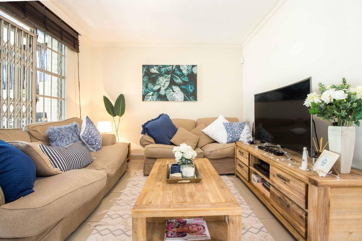 A comfortable living room featuring tiled flooring, crown molding, and a security gate on the window.