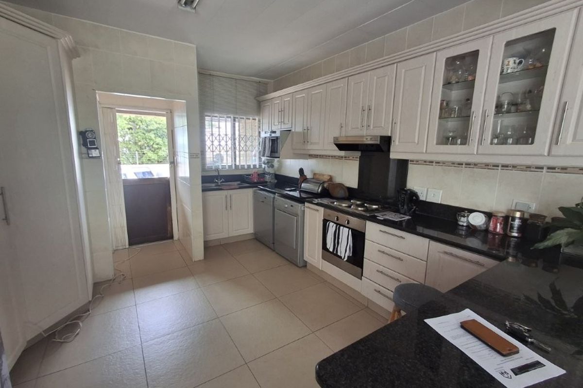 A functional kitchen featuring white cabinetry, granite countertops, integrated oven, and tiled flooring with direct access to an exterior area.