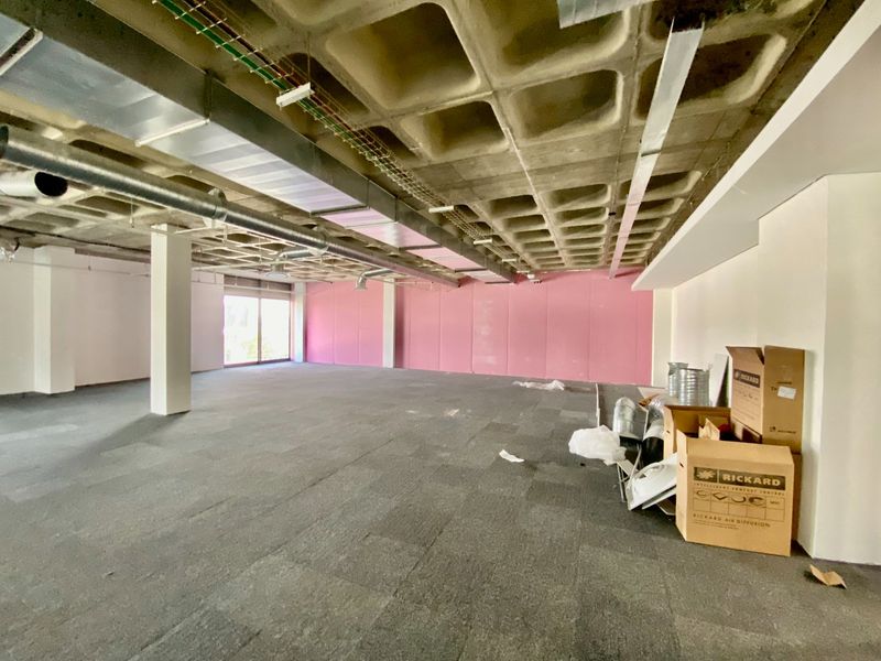 Spacious open-plan commercial office area featuring an exposed waffle slab ceiling, industrial HVAC ducting, and carpeted flooring, offering a blank canvas for customization.