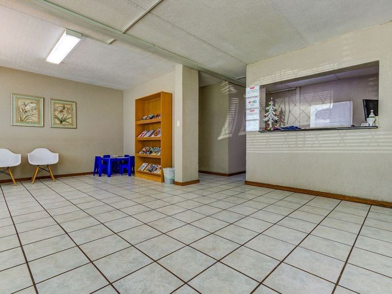 Commercial reception area featuring ceramic tile flooring, a built-in service counter, and drop ceiling with fluorescent lighting.