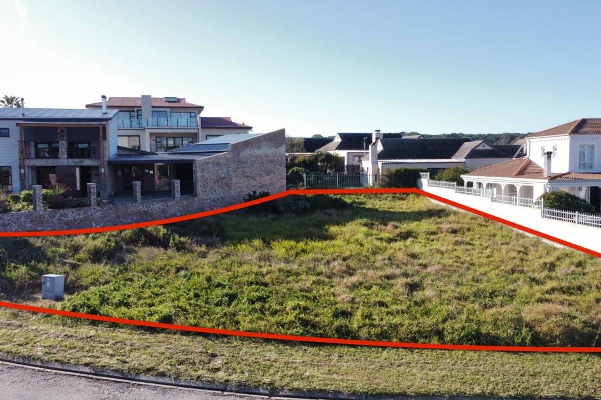 An elevated view of a vacant residential plot, clearly outlined in red, situated within an established neighborhood with surrounding residential properties.