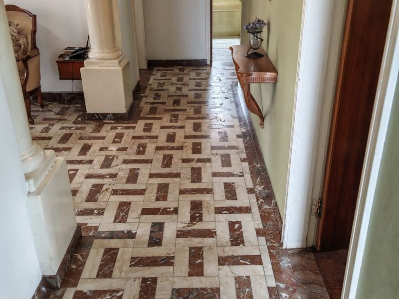 A hallway featuring decorative columns and patterned marble flooring, leading towards a bathroom area.