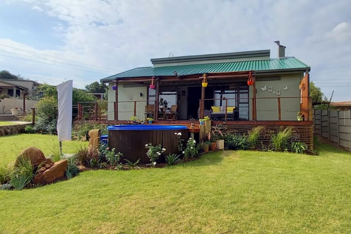 Rear view of the property featuring a green metal roof, a wooden deck, and a small plunge pool set within a landscaped garden.
