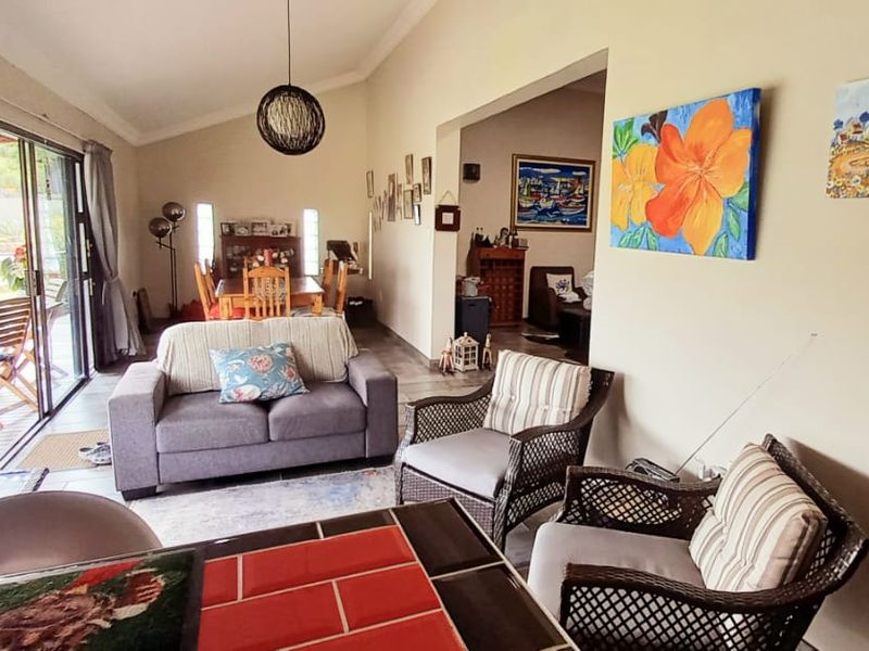 Spacious open-plan living and dining area featuring vaulted ceilings, tiled floors, and large sliding glass doors that provide seamless access to the outdoor patio.