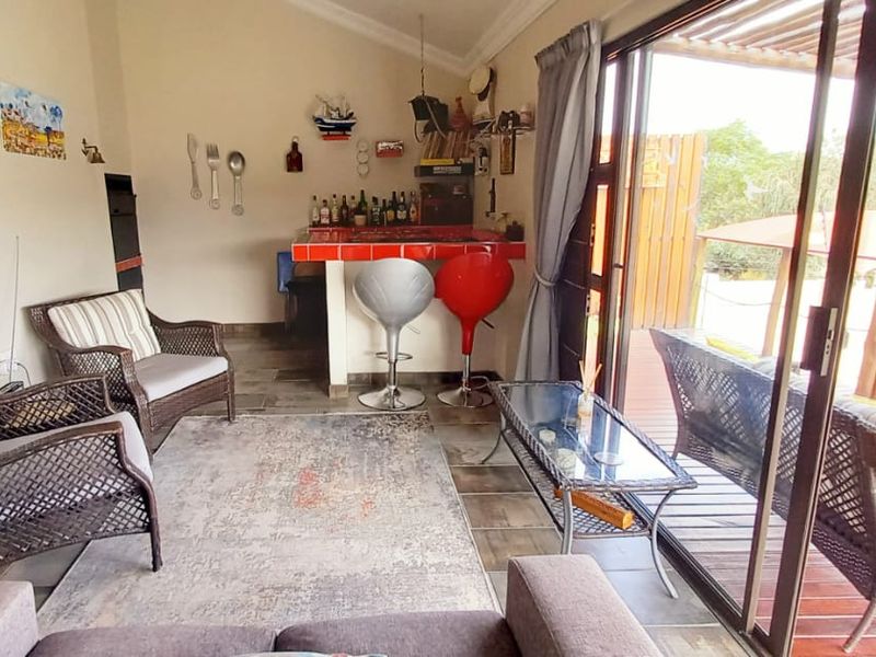 Covered patio area featuring a built-in bar counter, tiled flooring, and large sliding glass doors opening onto a timber deck with pergola.