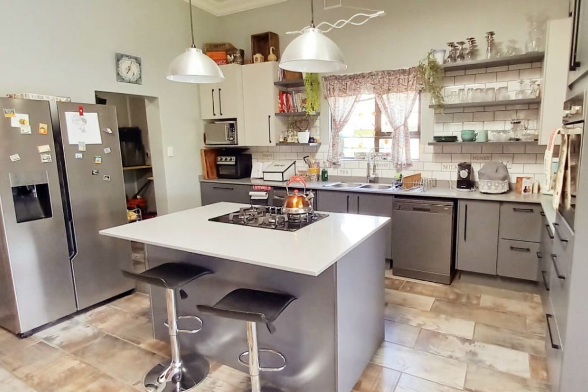 Modern kitchen featuring a central island with a gas hob, subway tile backsplash, ample cabinetry, and open shelving for a functional workspace.
