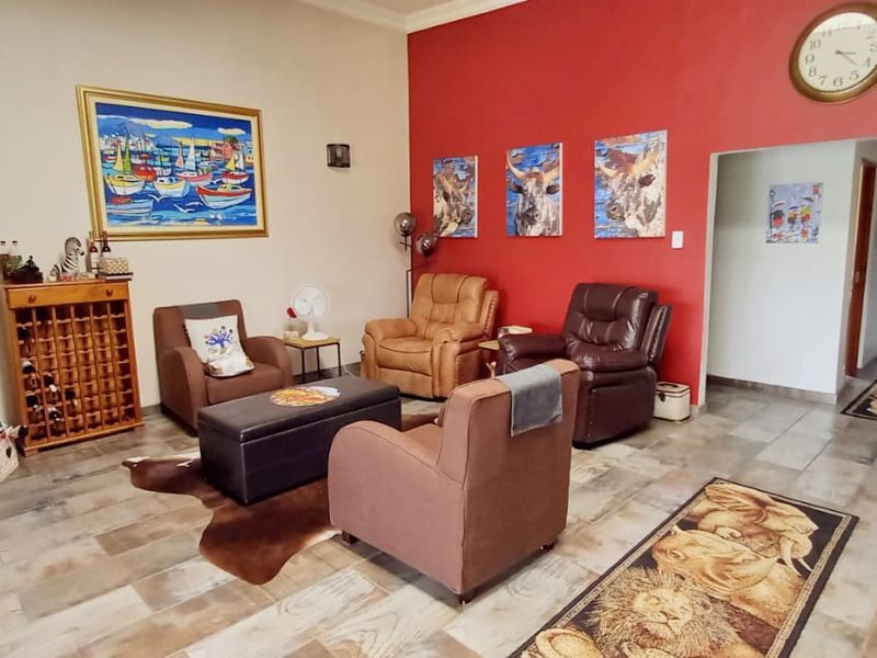 A spacious living area featuring tiled flooring and a bold red accent wall, providing a comfortable and functional space for relaxation.
