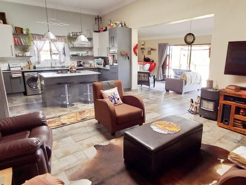 Spacious open-plan living area featuring a modern kitchen with a central island, gas hob, and tiled flooring, seamlessly flowing into the lounge space.