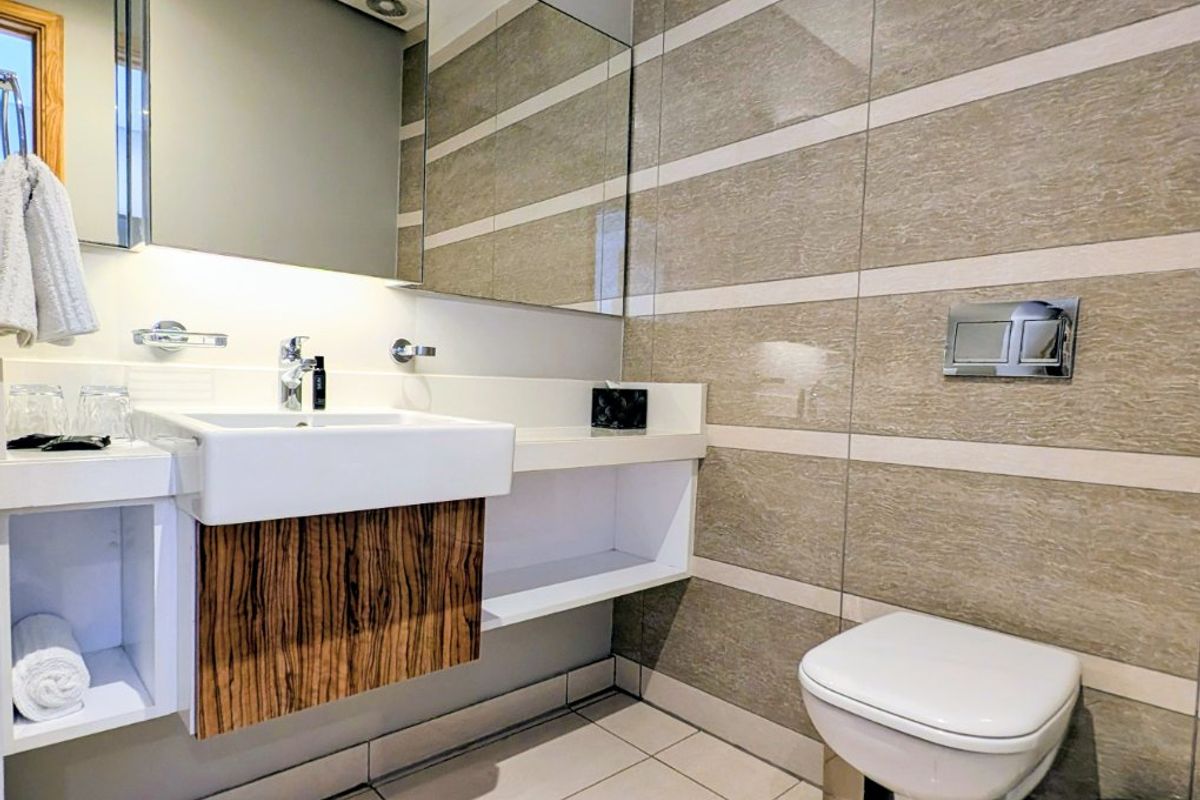 Modern bathroom featuring a wall-mounted toilet, sleek vanity basin with integrated storage, and contemporary tiled wall finishes.