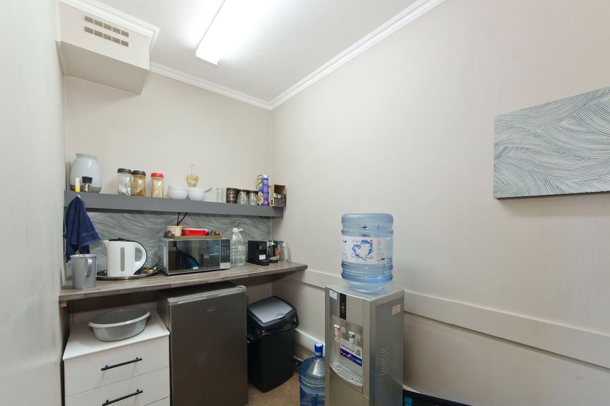 A compact commercial kitchenette area featuring a laminate countertop, built-in cabinetry, and a dedicated space for a water dispenser.