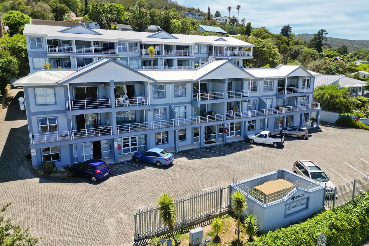Aerial view of a multi-story commercial building featuring multiple balconies, paved parking area, and secure gated entrance.