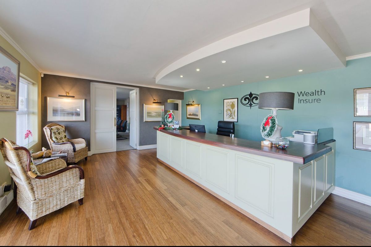 A professional commercial reception area featuring a built-in service counter, recessed ceiling lighting, and hardwood flooring.