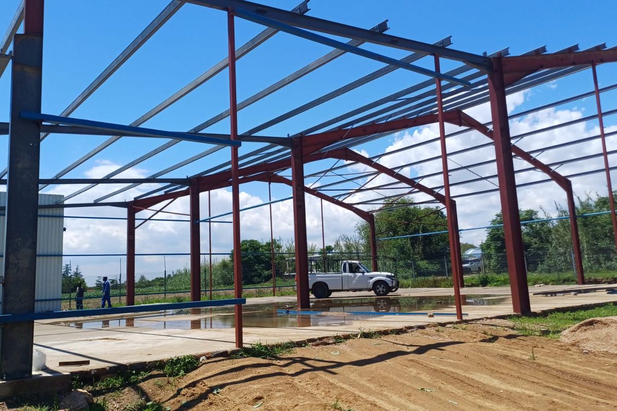 Industrial property under construction featuring a steel portal frame structure and a concrete slab foundation.