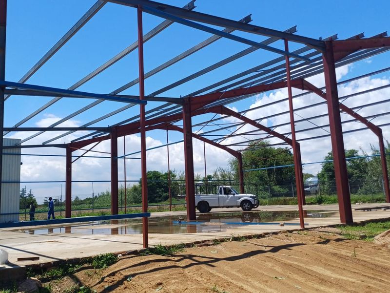 Industrial property under construction featuring a steel portal frame structure and a concrete slab foundation.