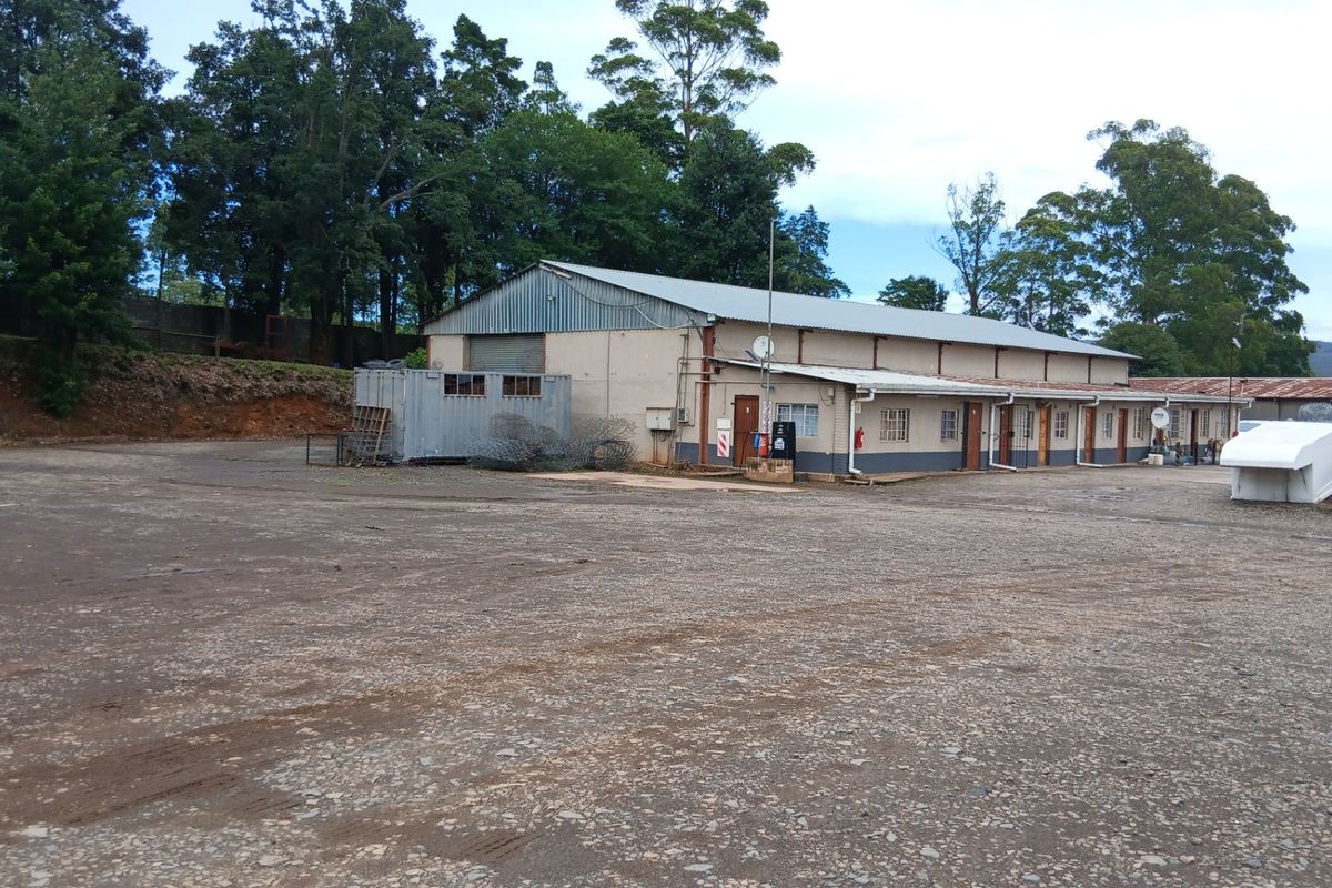 Large industrial-style farm building with a metal roof, concrete apron, and multiple access points, situated on a spacious gravel yard.