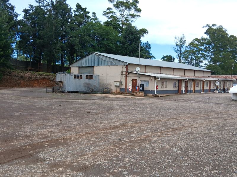 Large industrial-style farm building with a metal roof, concrete apron, and multiple access points, situated on a spacious gravel yard.