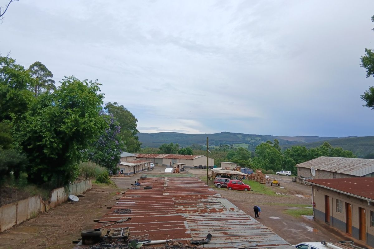 An elevated view of the farm property showing multiple outbuildings, corrugated metal roofing, and surrounding landscape.