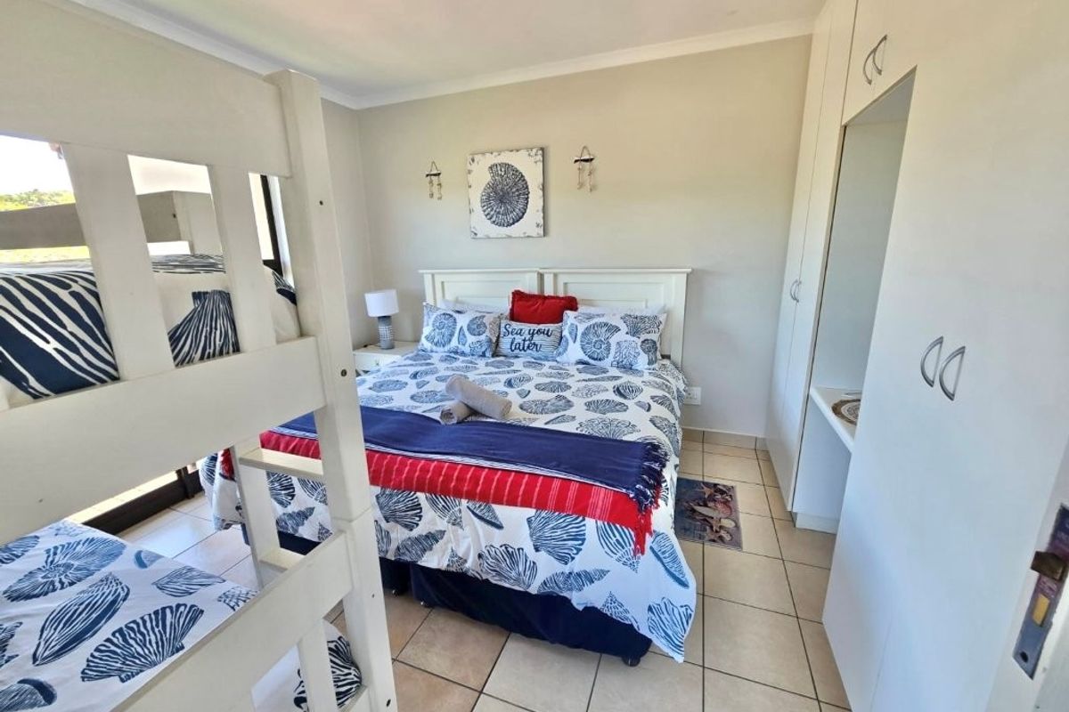 A functional bedroom featuring built-in cupboards, tiled flooring, and a coved ceiling, currently configured with a double bed and bunk beds.