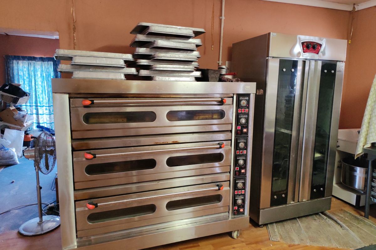 A functional commercial kitchen space featuring a large multi-deck oven and a stainless steel proofing cabinet, suitable for professional baking operations.