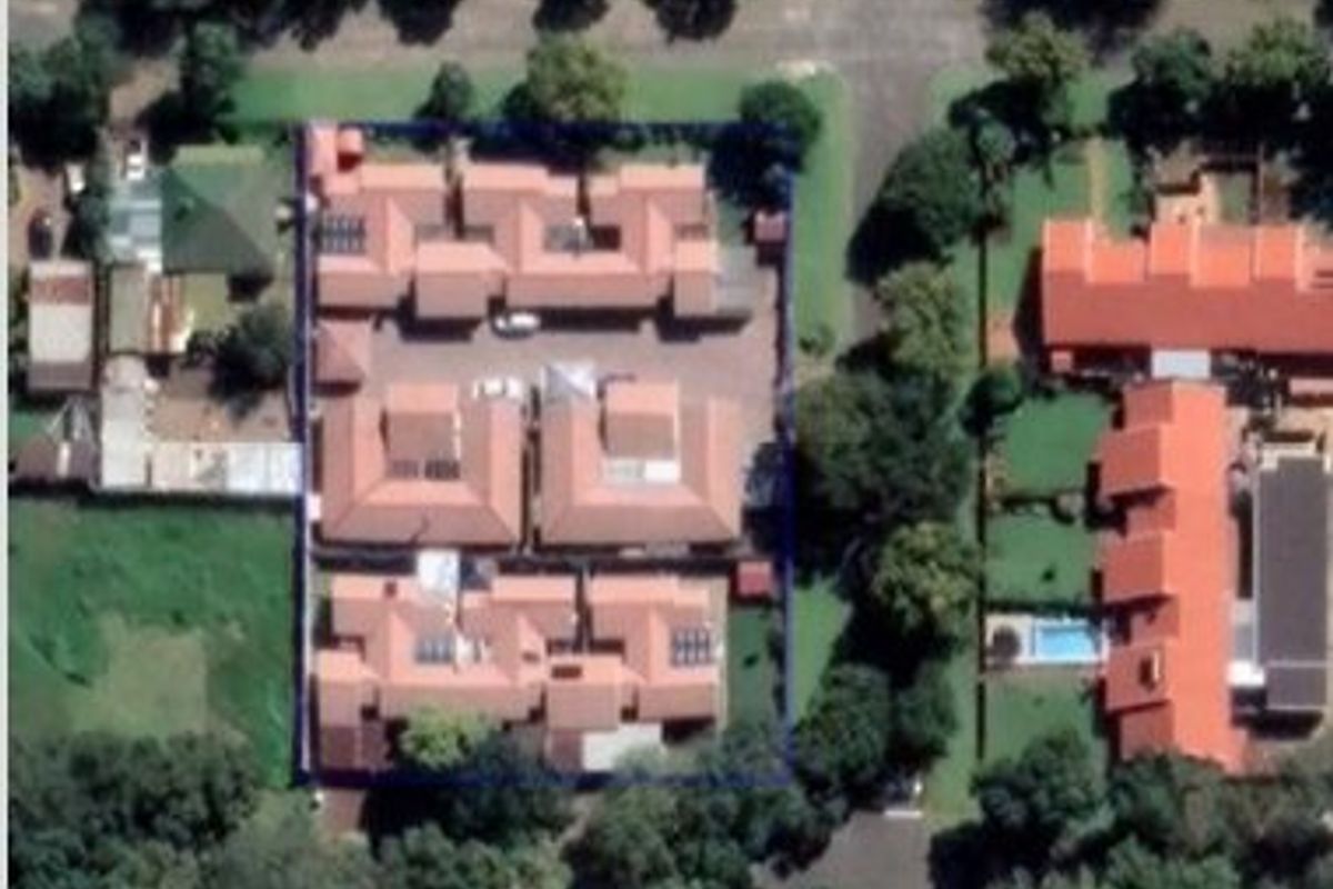 Aerial view of the townhouse complex showing the layout of the units, tiled roofs, and surrounding grounds.
