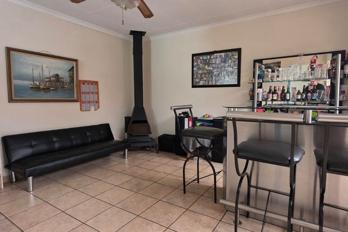 Living area featuring tiled flooring, a freestanding fireplace, and an exposed brick feature wall, providing a functional space for relaxation and entertainment.