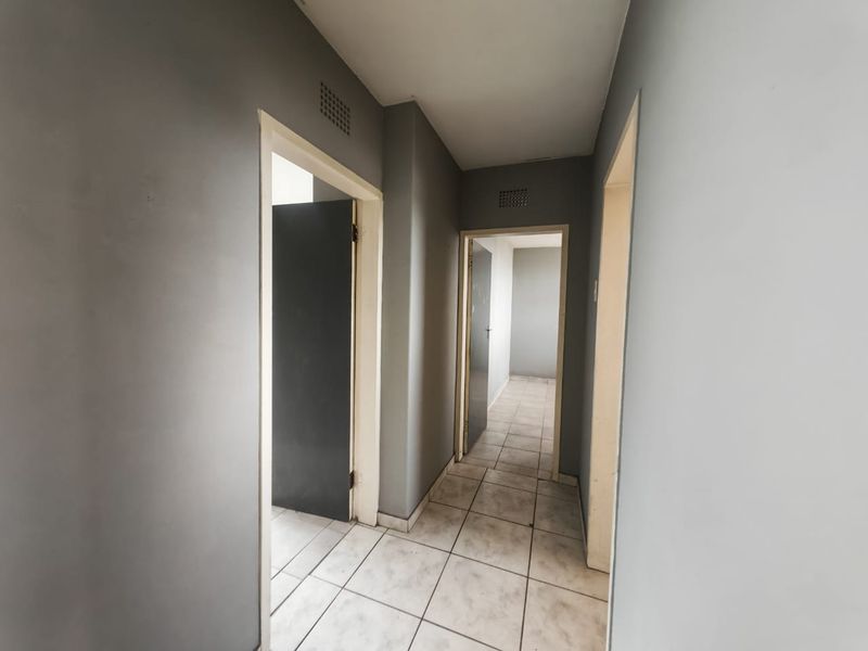 A functional hallway featuring tiled flooring and multiple internal doorways, connecting various rooms within the apartment.