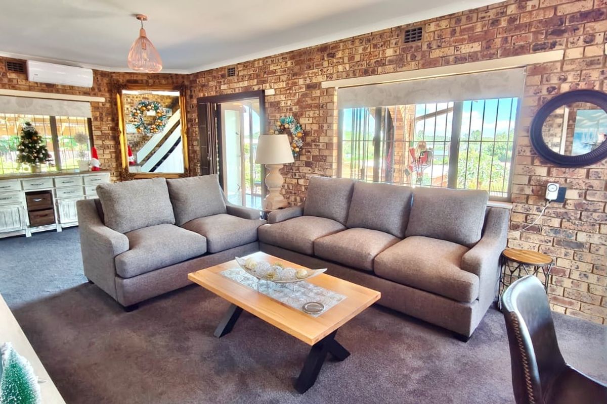 Spacious living room featuring exposed brick walls, large windows with security bars, and a wall-mounted split-system air conditioner.