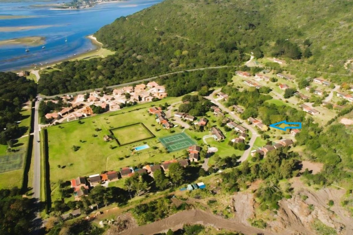 Aerial view of the residential estate featuring landscaped grounds, tennis courts, swimming pool, and proximity to the lagoon and coastal landscape.