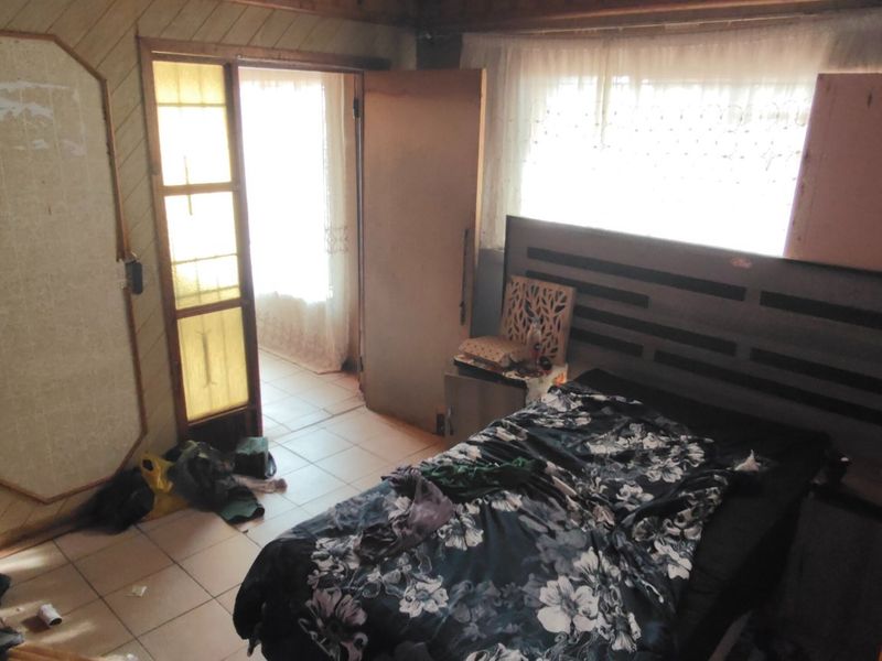 A bedroom featuring wood paneling and tiled flooring, requiring cosmetic updates to modernize the space.