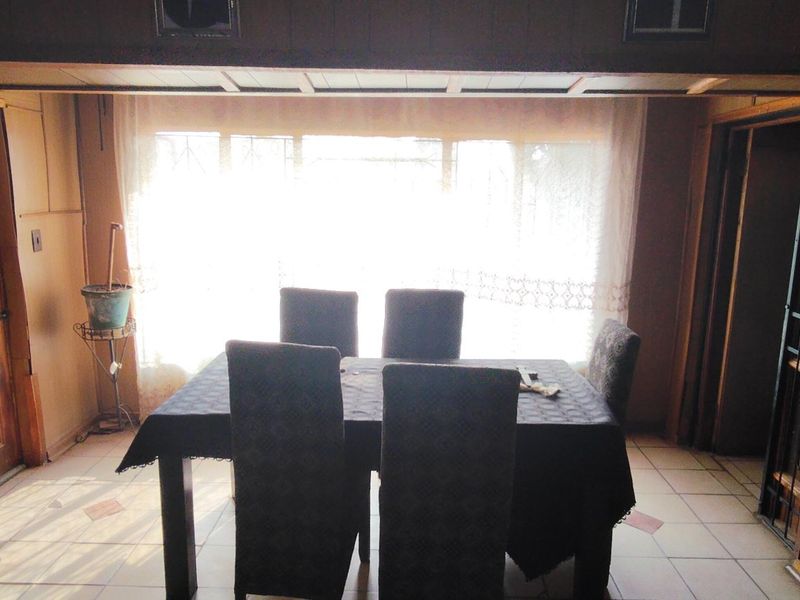 Dining room featuring timber wall paneling, tiled flooring, and a large window providing natural light.