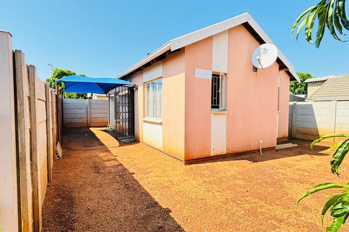 Rear view of the property featuring a precast concrete boundary wall, a shade sail covered area, and security features on windows and doors.