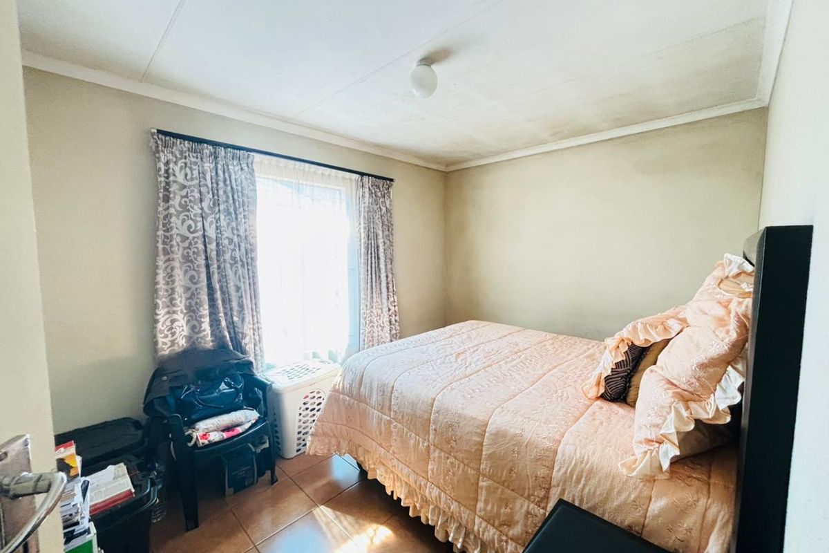 A compact bedroom featuring tiled flooring and natural light, currently requiring cosmetic updates to the ceiling and wall finishes.