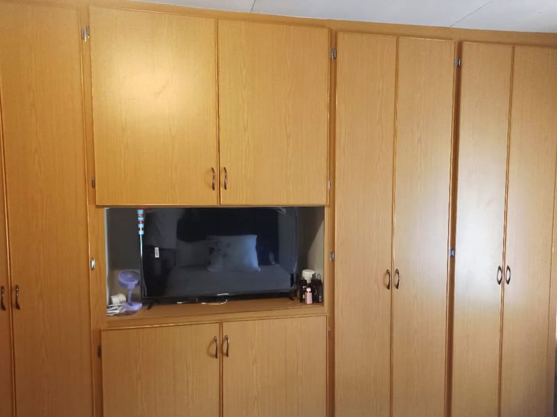 A bedroom featuring extensive built-in wooden cabinetry with integrated shelving and storage space.