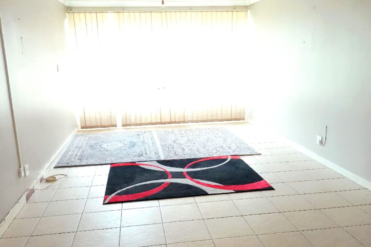 An open-plan living area featuring tiled flooring, vertical blinds, and basic lighting fixtures, offering a blank canvas for potential renovation.