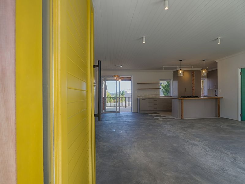 Spacious open-plan living and kitchen area featuring polished concrete floors, modern cabinetry, and seamless access to an outdoor patio through sliding glass doors.