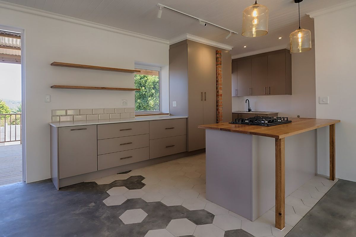 Modern kitchen featuring custom cabinetry, a timber breakfast bar with integrated gas hob, exposed brick detailing, and a unique hexagonal tiled floor transition.