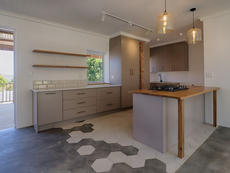 Modern kitchen featuring custom cabinetry, a timber breakfast bar with integrated gas hob, exposed brick detailing, and a unique hexagonal tiled floor transition.