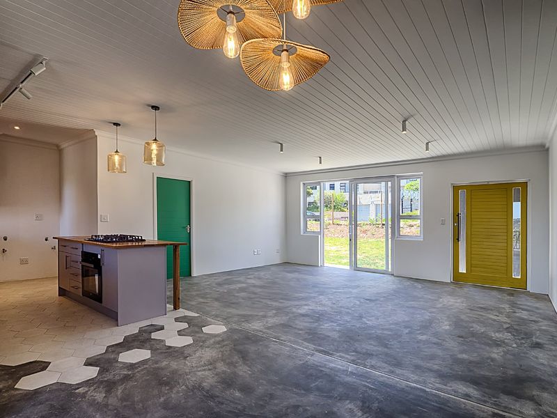 Spacious open-plan living area featuring a modern kitchen island with gas hob, polished concrete floors, and direct access to the garden through sliding doors.