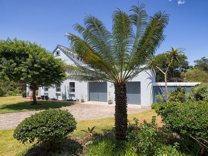 A well-maintained front exterior view of the property featuring a double garage, paved driveway, and established garden landscaping.