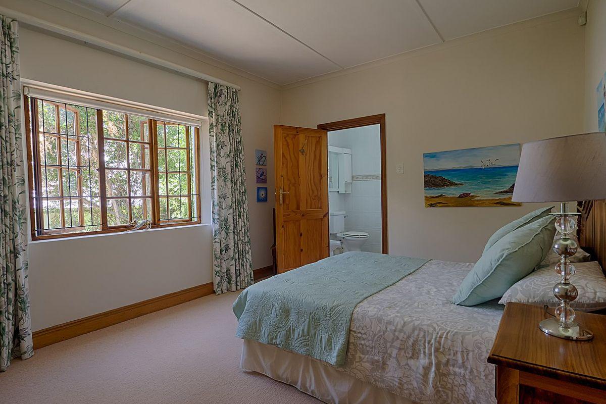 A well-maintained bedroom featuring carpeted flooring, timber window frames with security bars, and an adjoining en-suite bathroom.