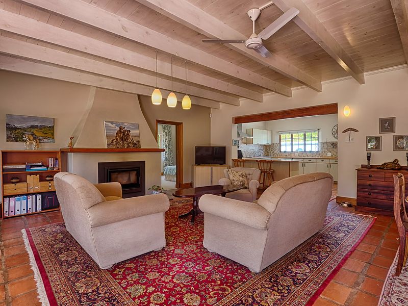 Spacious open-plan living area featuring exposed timber beams, a built-in fireplace, terracotta flooring, and an integrated kitchen with island seating.