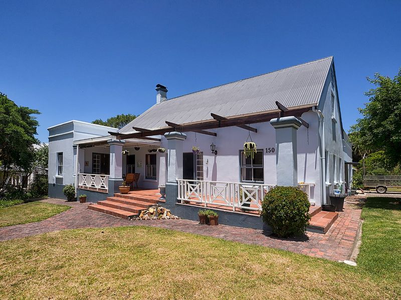 A charming single-story residence featuring a corrugated metal roof, a covered brick patio with timber pergola, and a well-maintained front garden.
