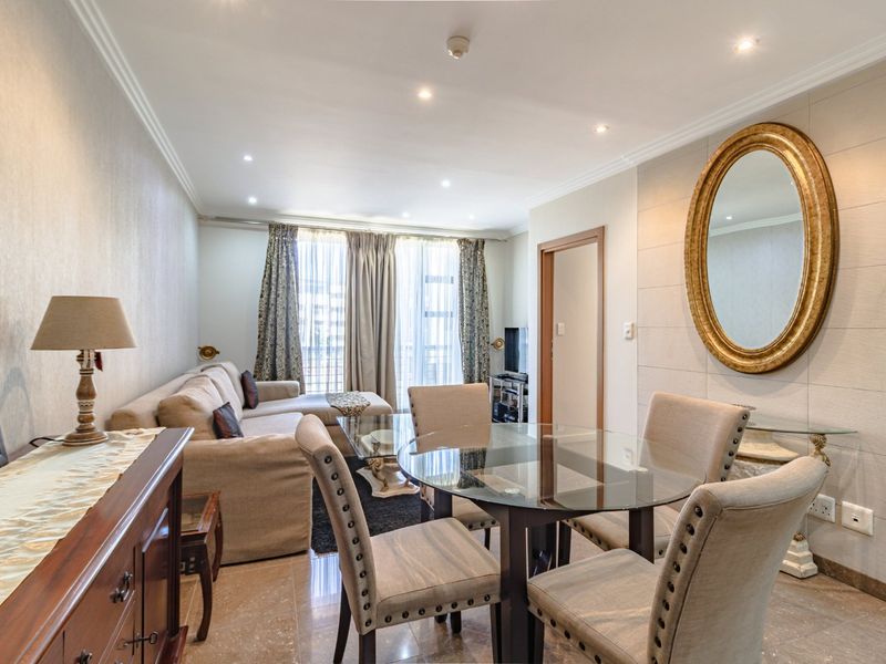 An open-plan living and dining area featuring tiled flooring, recessed downlighting, and access to a balcony through sliding glass doors.