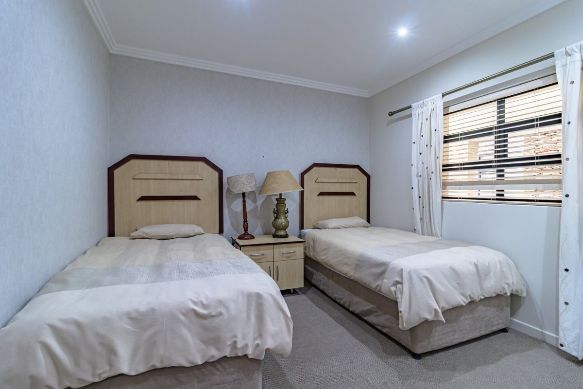 A functional bedroom featuring neutral wall finishes, recessed downlighting, and window blinds, providing a comfortable and well-maintained space.