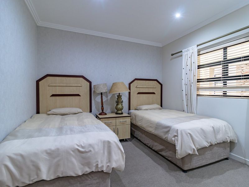 A functional bedroom featuring neutral wall finishes, recessed downlighting, and window blinds, providing a comfortable and well-maintained space.