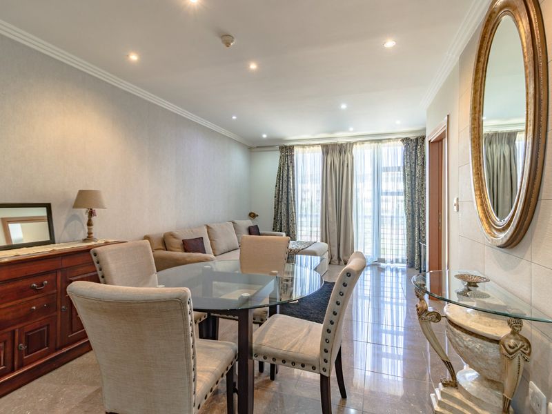 An open-plan living and dining area featuring tiled flooring, recessed downlighting, and direct access to a balcony through sliding glass doors.