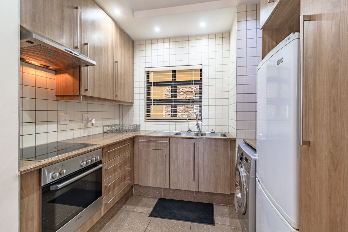 A well-maintained kitchen featuring wood-finish cabinetry, granite countertops, integrated appliances, and a tiled backsplash with a functional layout.