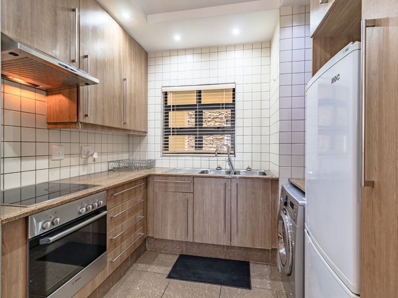 A well-maintained kitchen featuring wood-finish cabinetry, granite countertops, integrated appliances, and a tiled backsplash with a functional layout.