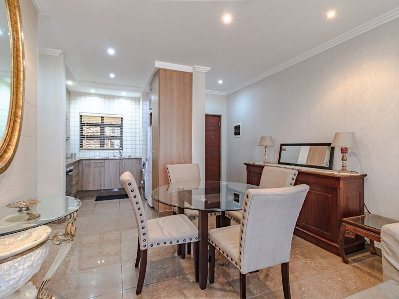 An open-plan living and dining area featuring tiled floors, recessed lighting, and a functional kitchen with built-in cabinetry and appliances.